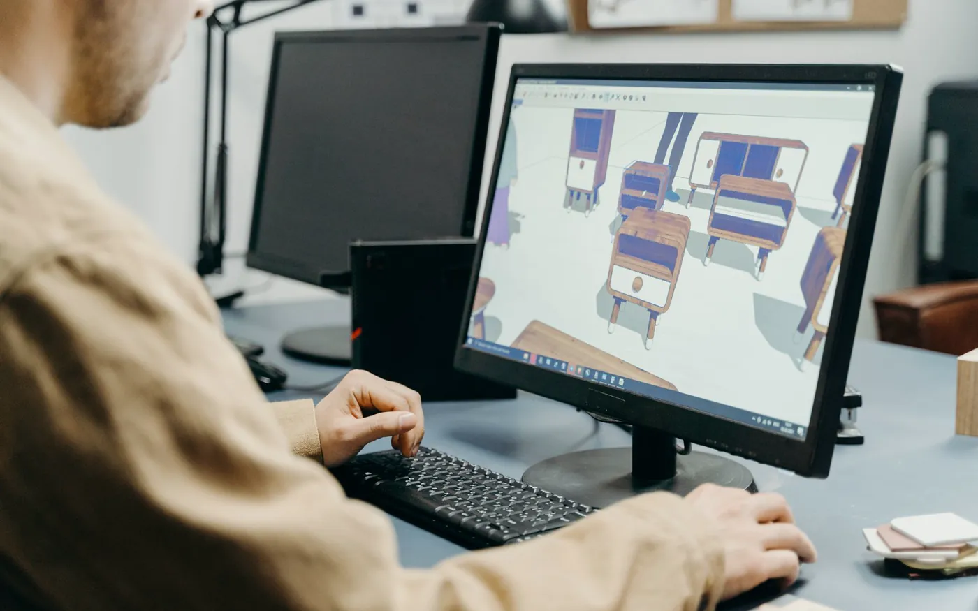 3D dolap tasarım aracında bilgisayar ekranındaki dolap ve mobilya modelleri üzerinde çalışan tasarımcı