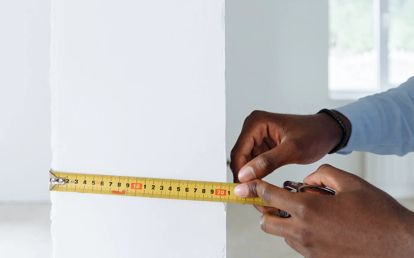Duvar önünde şerit metreyle dolap yeri ölçen eller